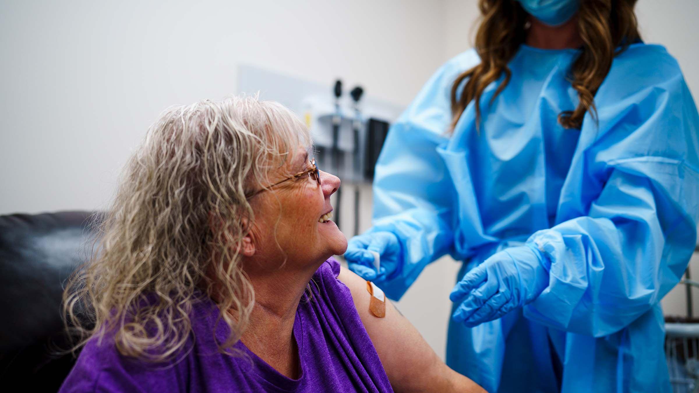 Pinnacle participant smiling up at a nurse administering a vaccine